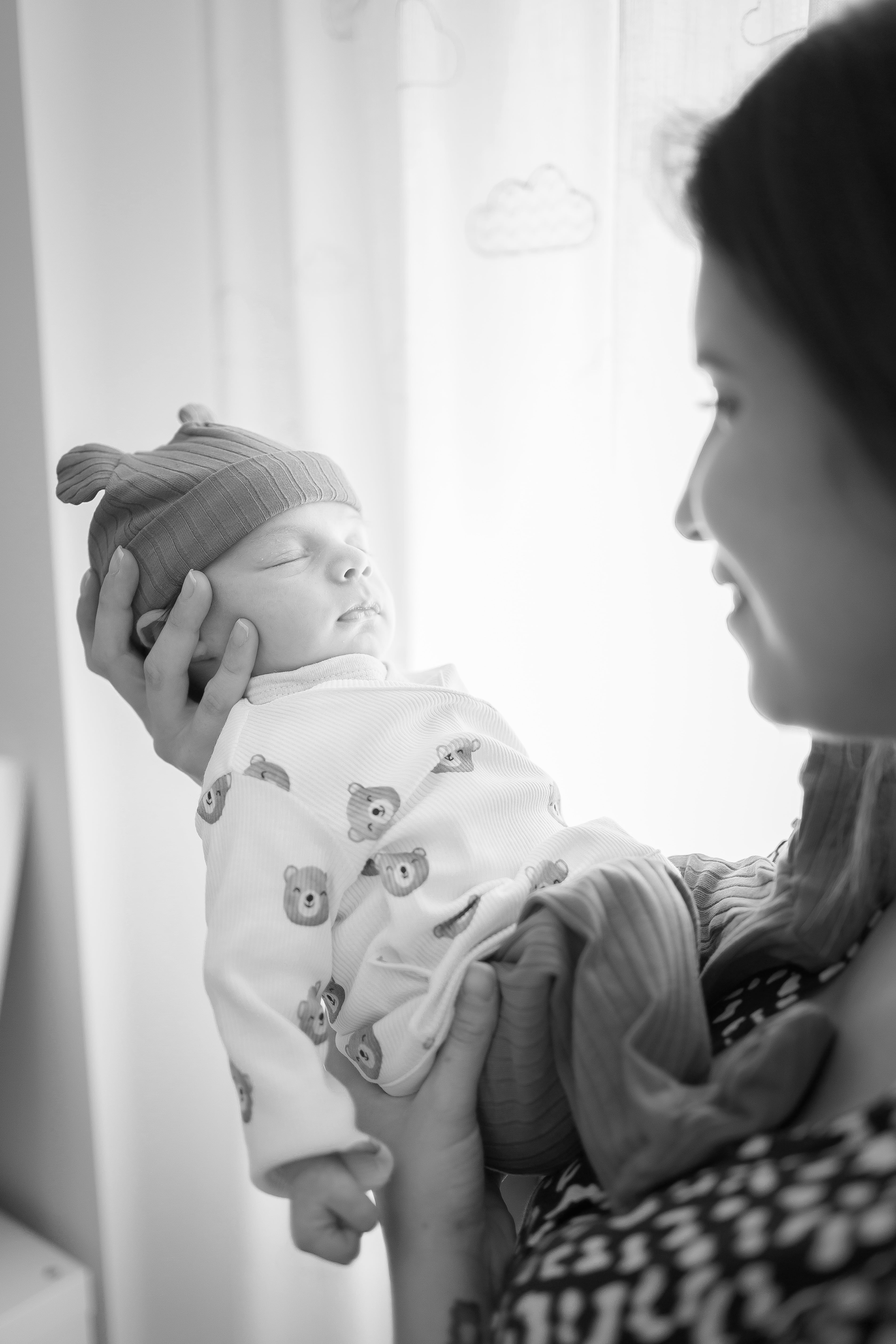 Madre con su bebé junto a una ventana en una fotografía en blanco y negro